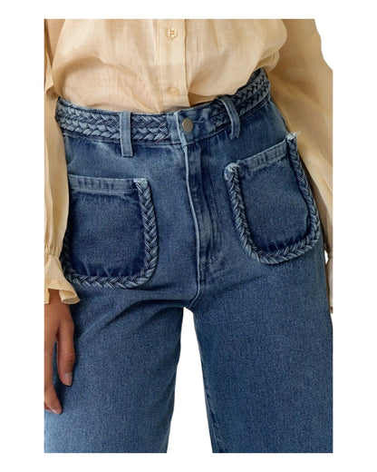 High waist blue denim jeans with braided waistband detail, straight wide-leg fit, and extra-high waist. Made from no-stretch fabric with front pockets and a longer inseam, ideal for a slender silhouette. Medium blue washed denim.