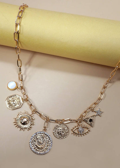 Gold charm necklace featuring celestial charms—sun, moon, stars, and evil eye—with rhinestone accents.