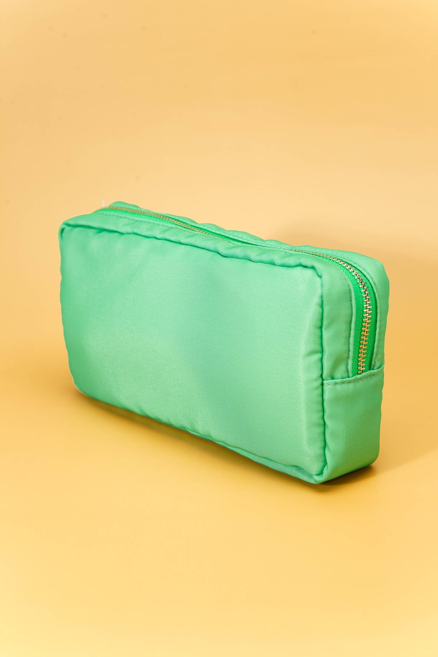 Small nylon cosmetic bag with gold-tone hardware and a zip closure, ideal for travel and everyday organization. 6 colors to choose from: Black, Green, Blue, Peach, White, Pink. 