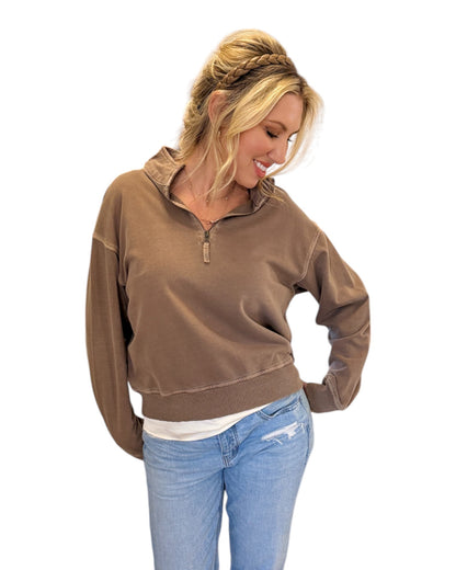 Woman smiling and wearing jeans with the Mocha French Terry Half-Zip Sweatshirt made from 100% cotton with a washed finish, featuring a half-zip design, ribbed hem and cuffs, and a relaxed fit for casual styling.