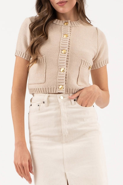 Taupe cropped knit cardigan with gold button hardware, short sleeves, and ribbed trim details.