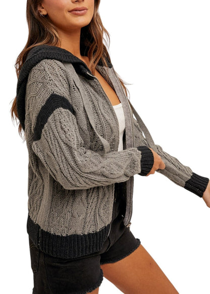 Women's color-block cable knit hoodie sweater with zippered front, soft cotton blend, and cozy hood in gray and black. 