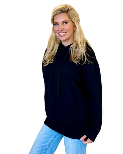 Woman wearing a soft, black oversized hoodie sweater.