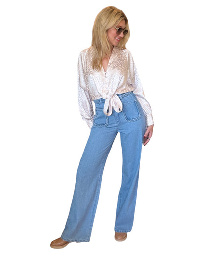 High waist blue denim jeans with braided waistband detail, straight wide-leg fit, and extra-high waist. Made from no-stretch fabric with front pockets and a longer inseam, ideal for a slender silhouette. Medium blue washed denim.