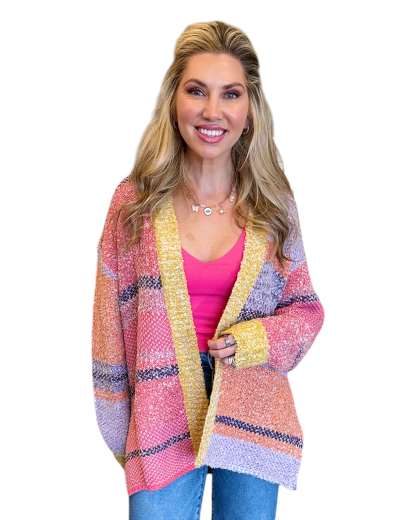 Woman wearing the Tenley Knit Dreamer Cardigan in vibrant purple, coral, and yellow tones, paired with a bright pink tank top and mid-rise wide-leg jeans. She accessorizes with a custom charm necklace made at Wish Upon Boutique, smiling against a white background.