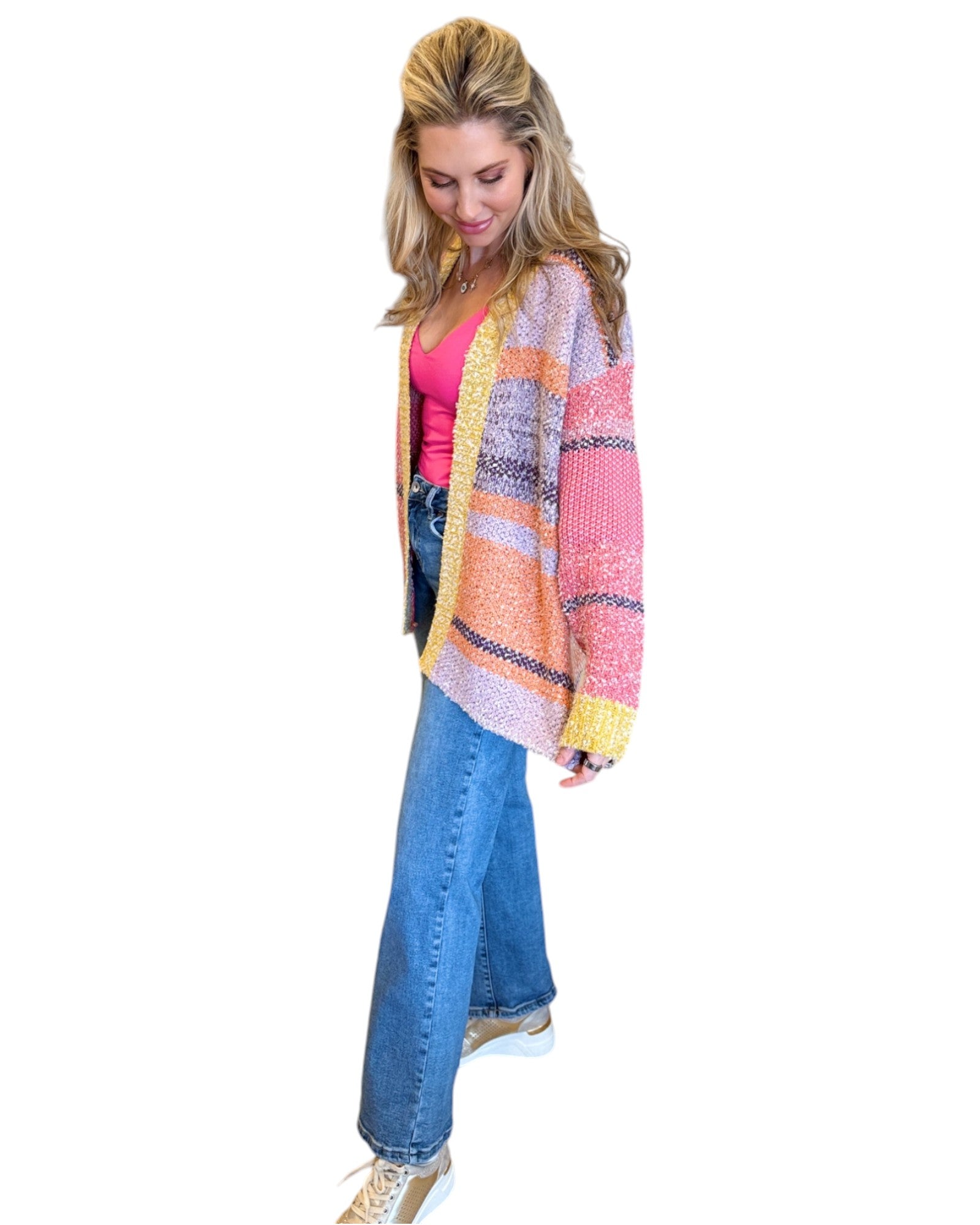 Woman wearing the Tenley Knit Dreamer Cardigan in vibrant purple, coral, and yellow tones, paired with a bright pink tank top and mid-rise wide-leg jeans. She accessorizes with a custom charm necklace made at Wish Upon Boutique, smiling against a white background.