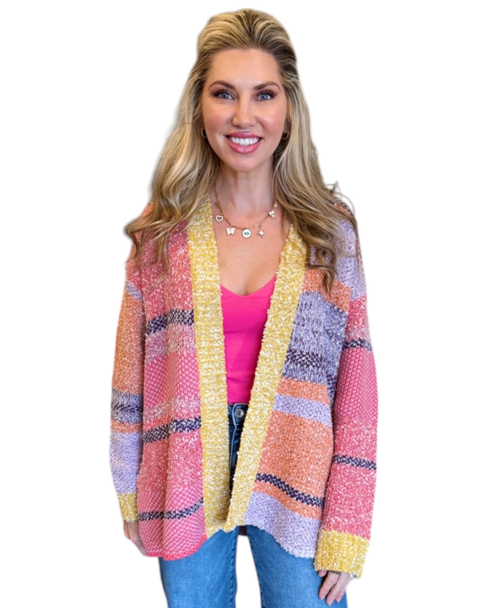 Woman wearing the Tenley Knit Dreamer Cardigan in vibrant purple, coral, and yellow tones, paired with a bright pink tank top and mid-rise wide-leg jeans. She accessorizes with a custom charm necklace made at Wish Upon Boutique, smiling against a white background.