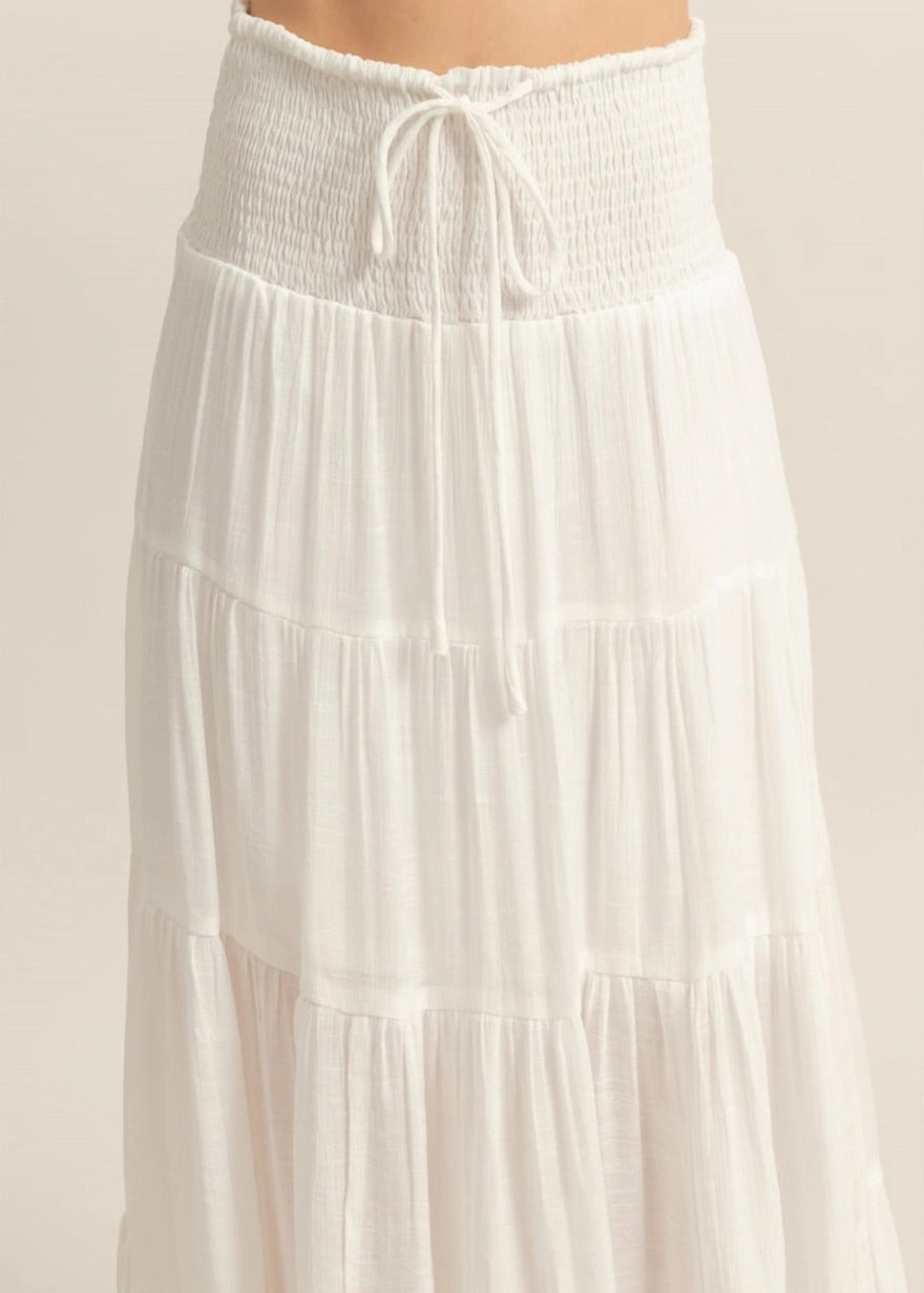 White tiered maxi skirt with a smocked elastic waistband and ankle-skimming hem.