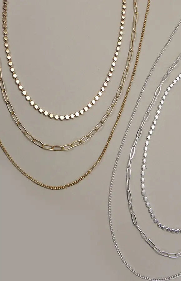 Silver multi-layer chain necklace with three distinct chains and adjustable length.